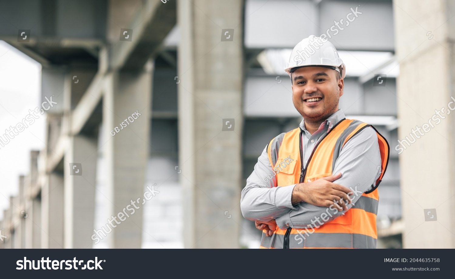 Asian engineer handsome man or architect looking construction with white safety helmet in construction site. Standing at highway concrete road site. #2044635758