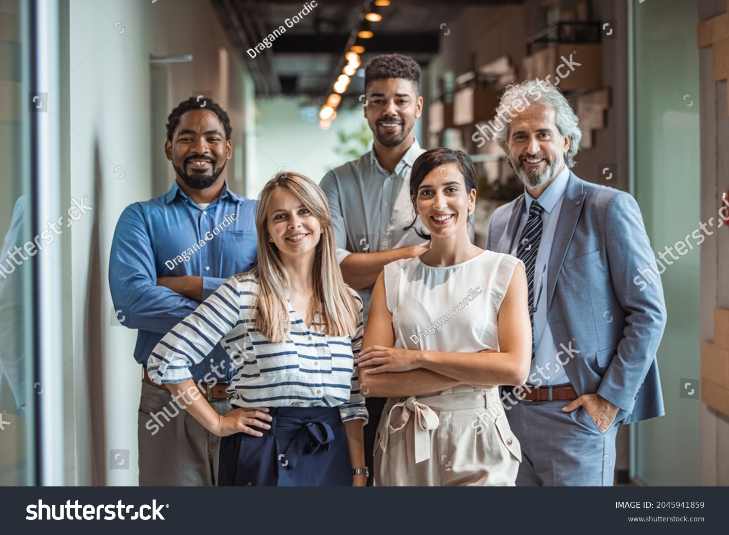 Shot of a group of well-dressed businesspeople standing together. Successful business team smiling teamwork corporate office colleague. Ready to make success happen #2045941859