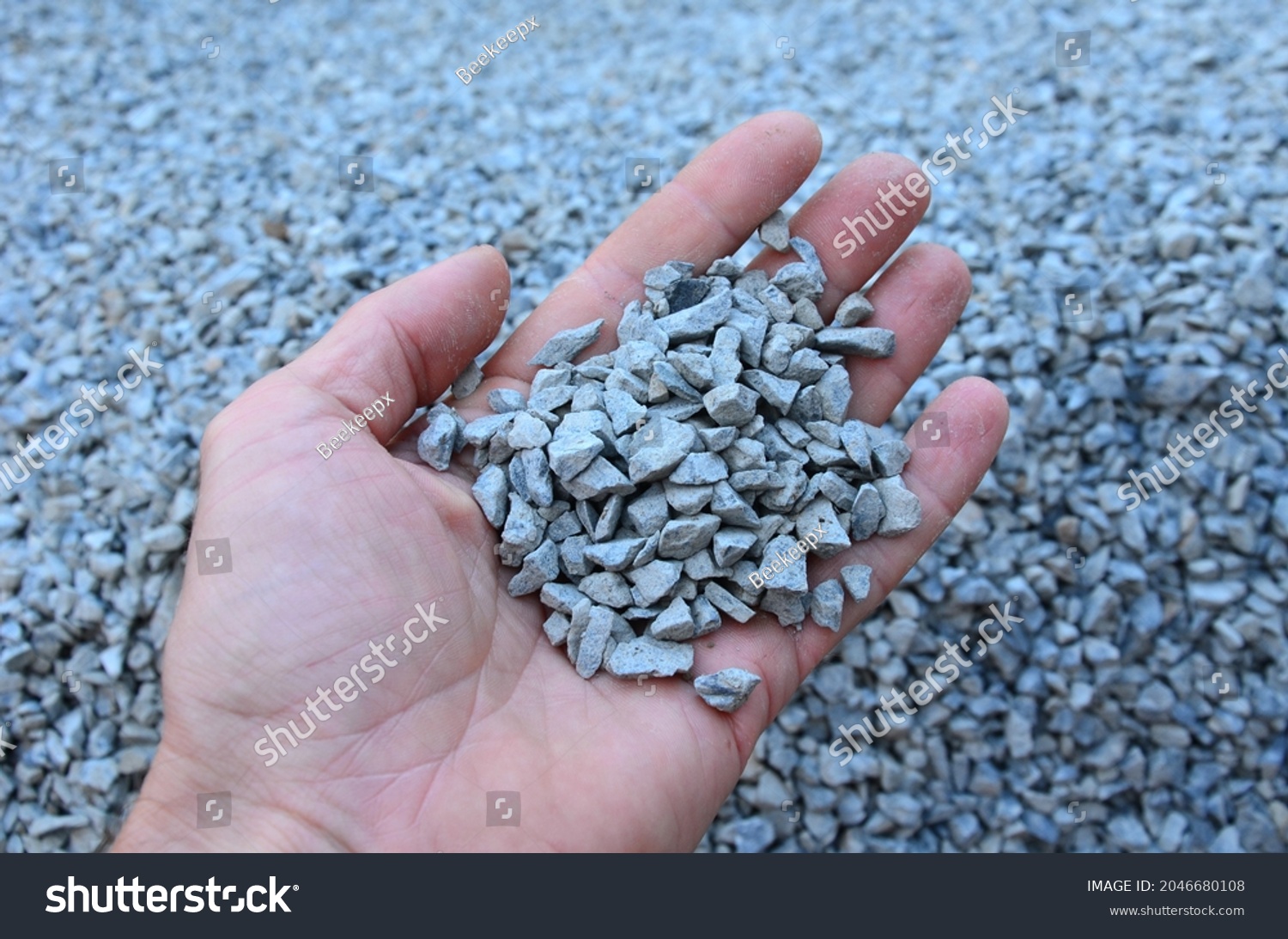 man holds in his hand a sample of stone gravel or pebbles of one size. Marble white gravel and gray brown pebbles straight from the quarry. #2046680108