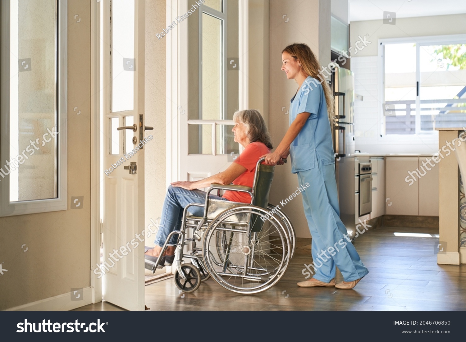 Caregiver or nurse pushes a paralyzed elderly woman in a wheelchair in a retirement home #2046706850