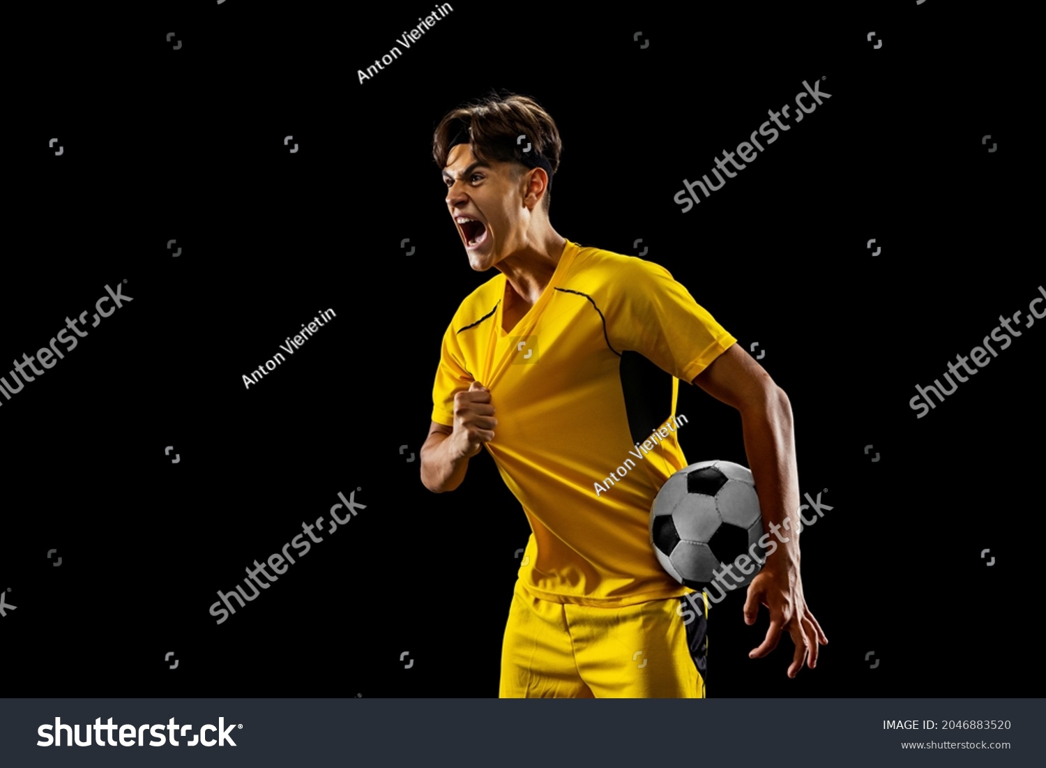 After winning game. Happy proud male football player in yellow uniform isolated over dark background. Successful competition. Concept of action, speed, energy, sport, competition and ad. #2046883520