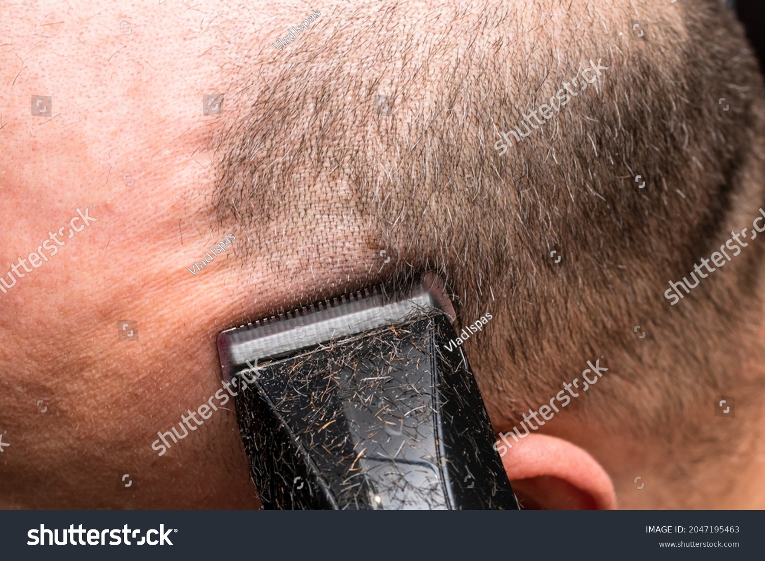 Man shaving or trimming his hair using a hair clipper #2047195463