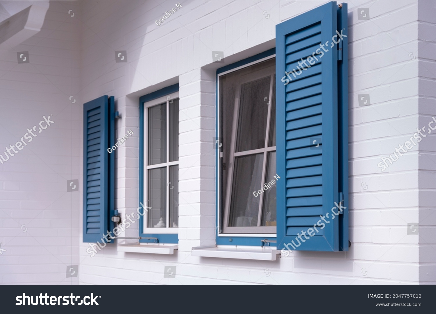 blue louvered window shutters on a white house #2047757012