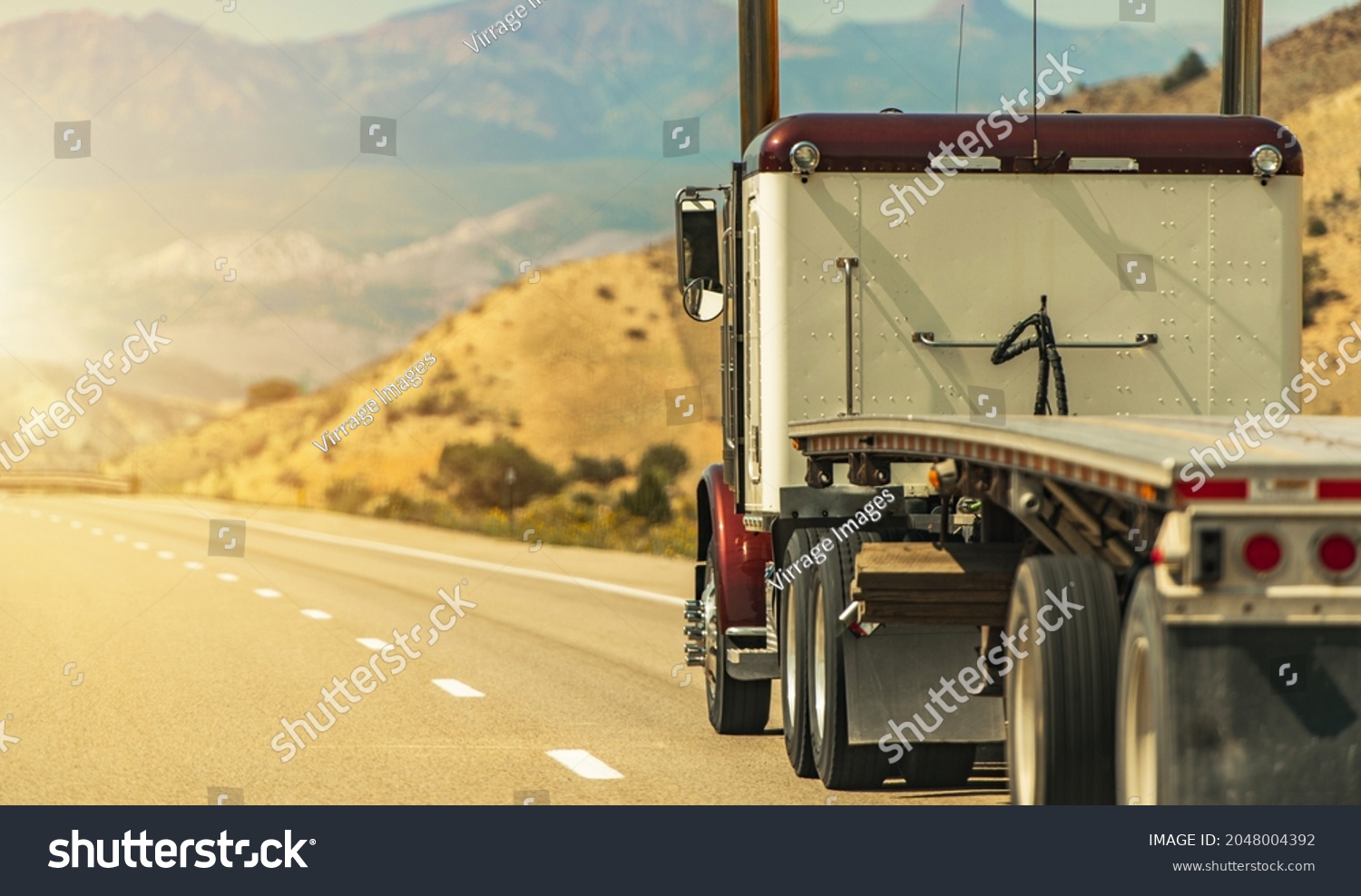 Heavy Duty Freight Theme. Semi Truck with Flatbed Trailer on a Scenic Utah Interstate 70 Highway. American Transportation Industry. #2048004392