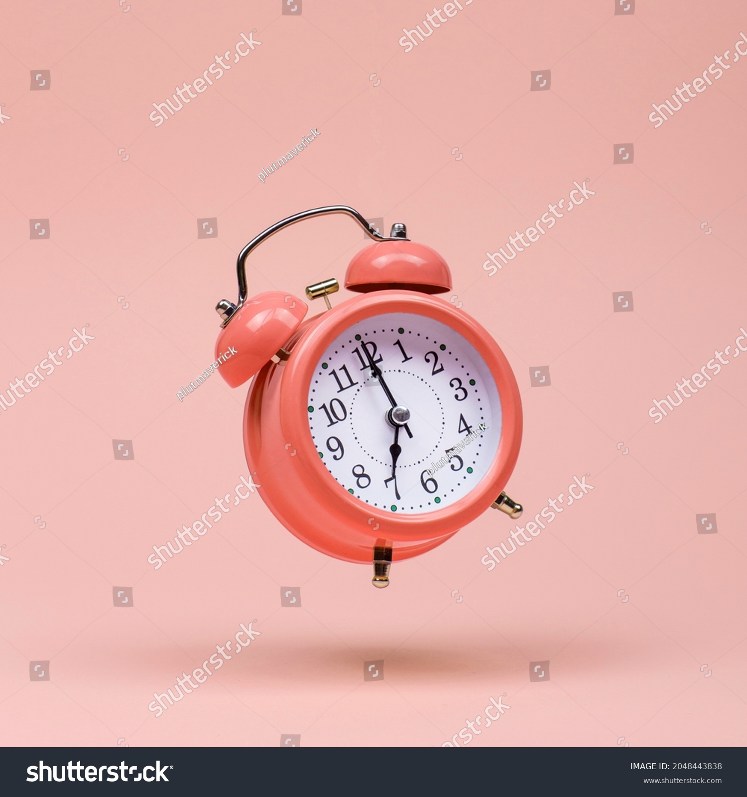 The pink alarm clock is levitate in the air, against pink background. The concept of time, copy space. #2048443838