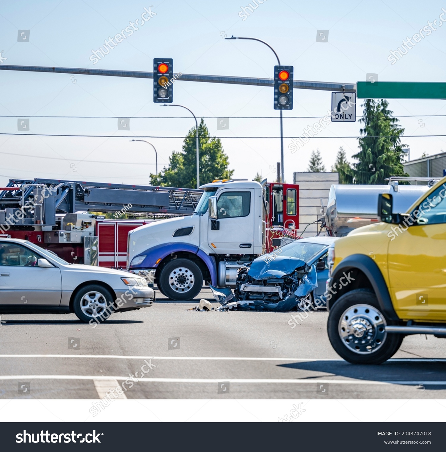 Damaged cars after a car accident crash involving a big rig semi truck with semi trailer at a city street crossroad intersection with traffic light and rescue services to help the injured #2048747018