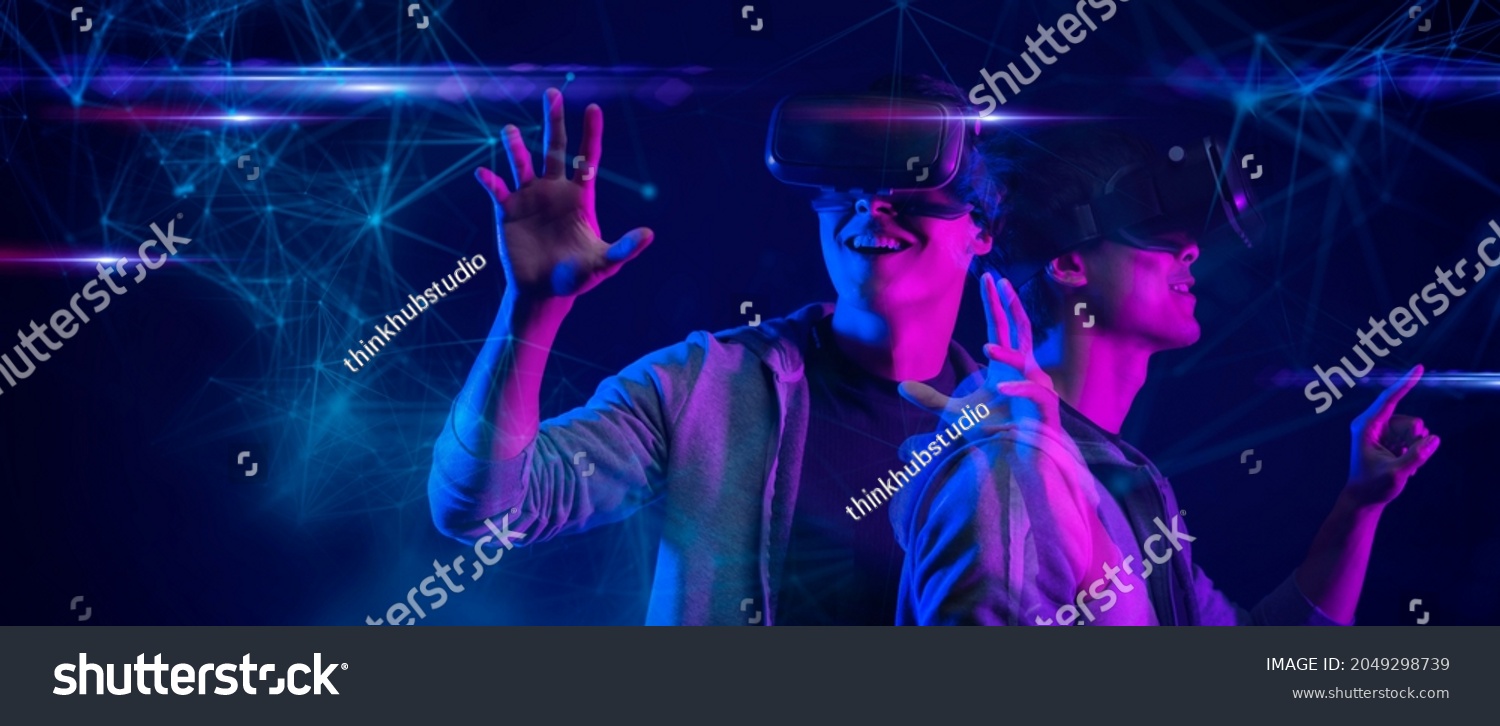 Teenager having fun play metaverse VR virtual reality glasses Esport game futuristic neon colorful background, future digital technology NFT game and entertainment #2049298739
