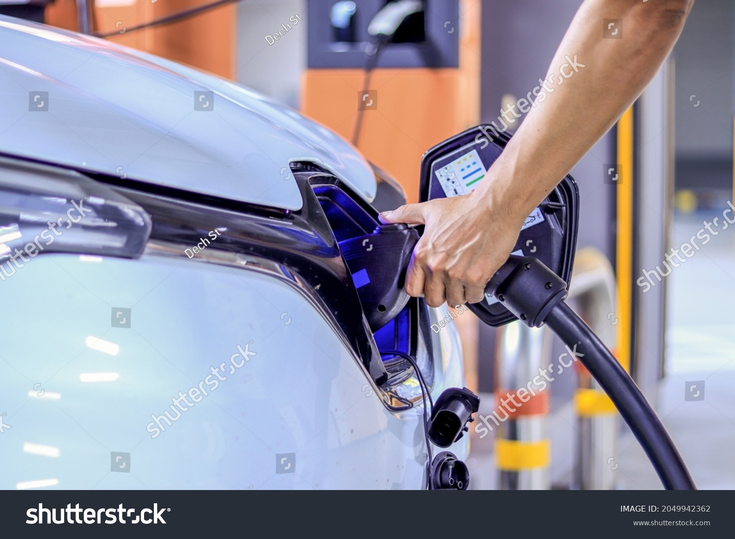 Human hand is holding Electric car, Plug the charger access to vehicle electrification #2049942362