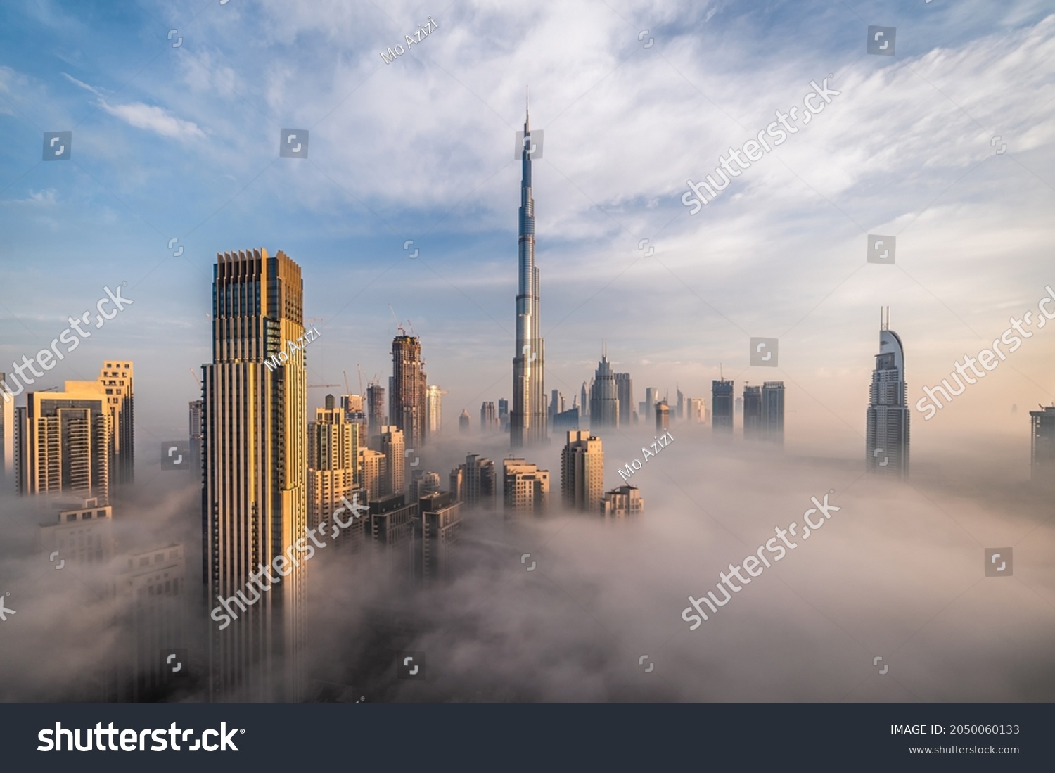 Downtown Dubai with skyscrapers submerged in think fog. Picture taken from unique view. Tall buildings. Early morning glow.  #2050060133