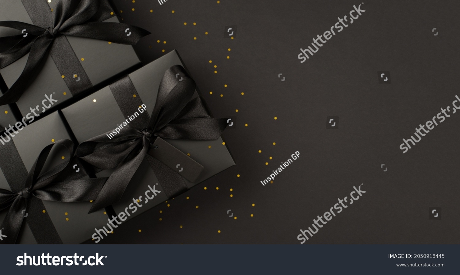 Top view photo of black gift boxes with black ribbon bow tag and golden confetti on isolated black background with blank space #2050918445