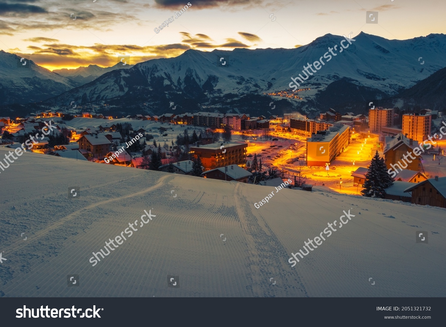 Beautiful alpine winter ski resort with majestic street lights at dawn. Mountain resort and ski slopes at sunrise, La Toussuire, Rhone Alps, France, Europe #2051321732