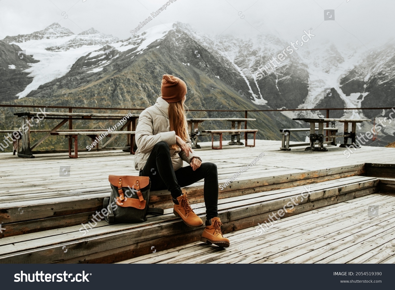 Girl traveler with backpack enjoy mountain nature sitting on wooden bridge. Cheget, Kabardino-Balkaria, Russia. #2054519390