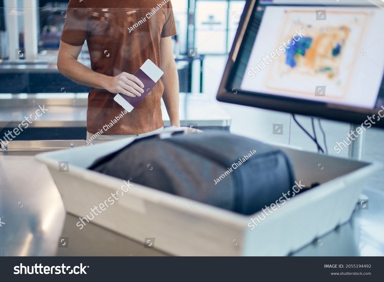Airport security check. Young man waiting for x-ray control his bag.
 #2055194492