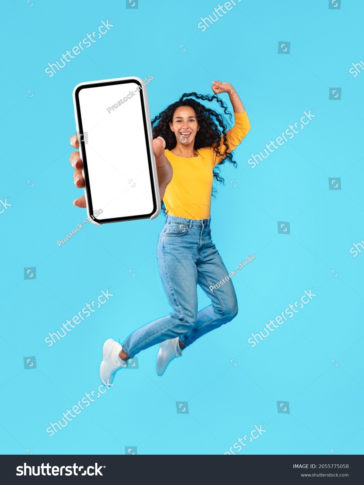 Happy Arab Female Jumping Up Showing Big Blank Smartphone Screen Advertising Great Application On Blue Background. Middle-Eastern Woman Holding Huge Cellphone For App Advertisement. Mockup, Collage #2055775058