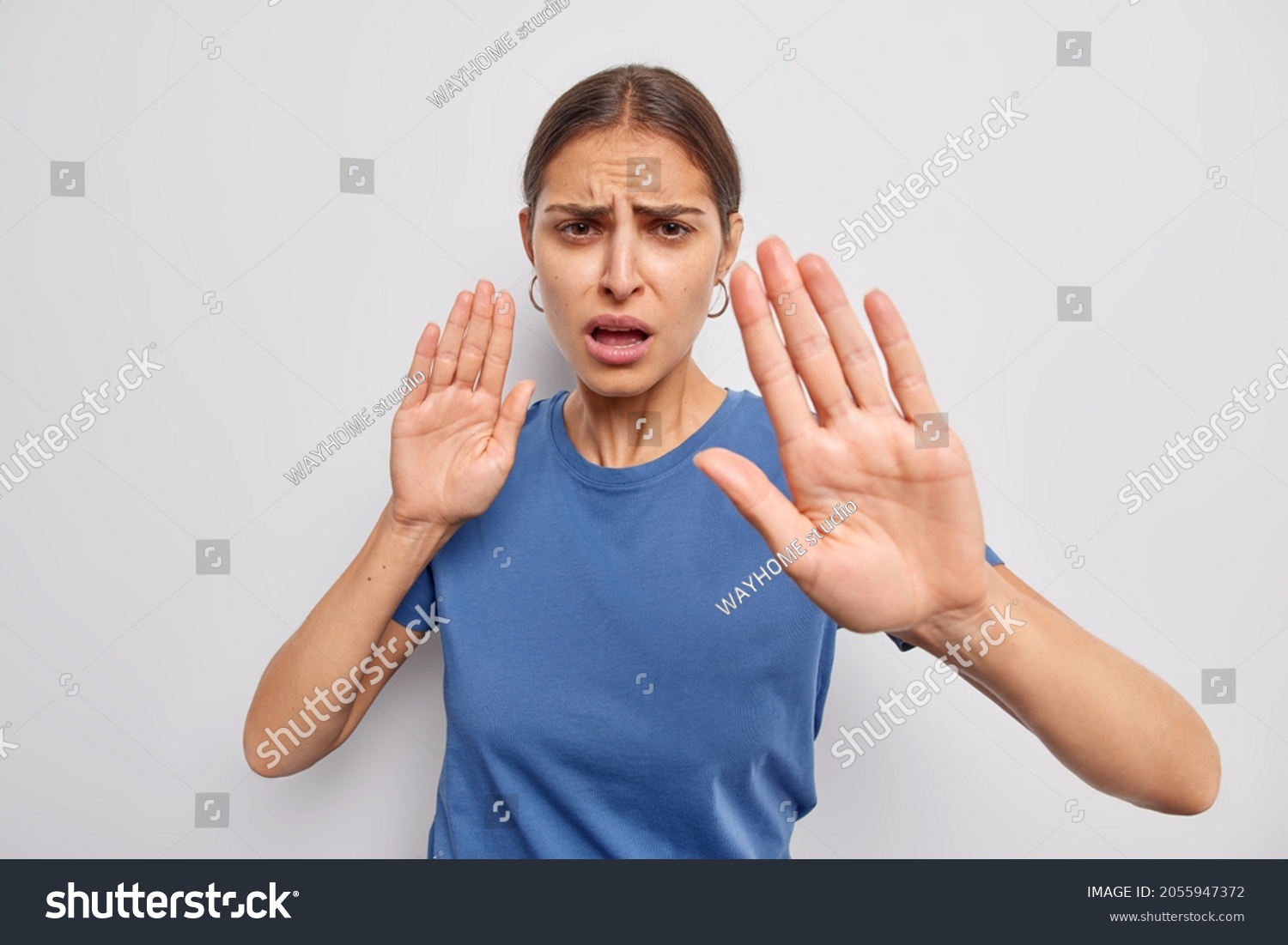Do not come closer. Displeased woman shows her denial opinion says stay away from me calm down or slow asks to keep distance demonstrates taboo gesture dressed casually isolated over white wall #2055947372