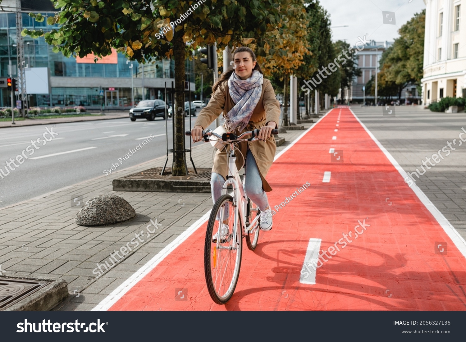 traffic, city transport and people concept - woman riding bicycle along red bike lane or two way road on street #2056327136