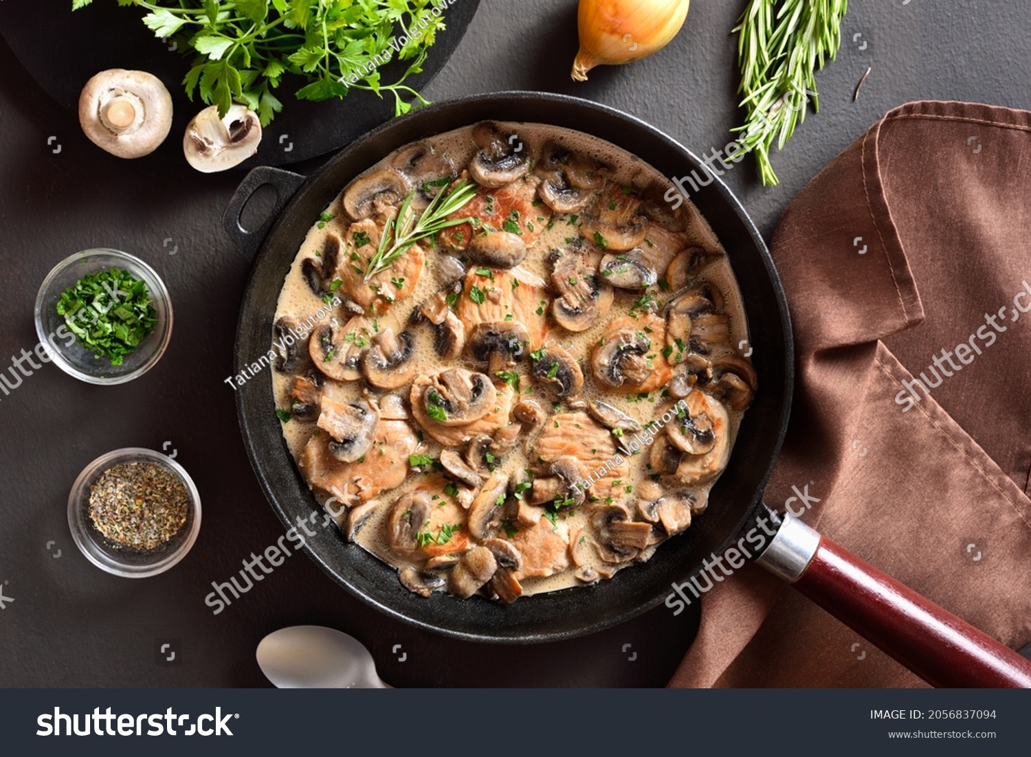 Pork medallions with mushroom gravy in cast iron pan over dark stone background. Top view, flat lay #2056837094