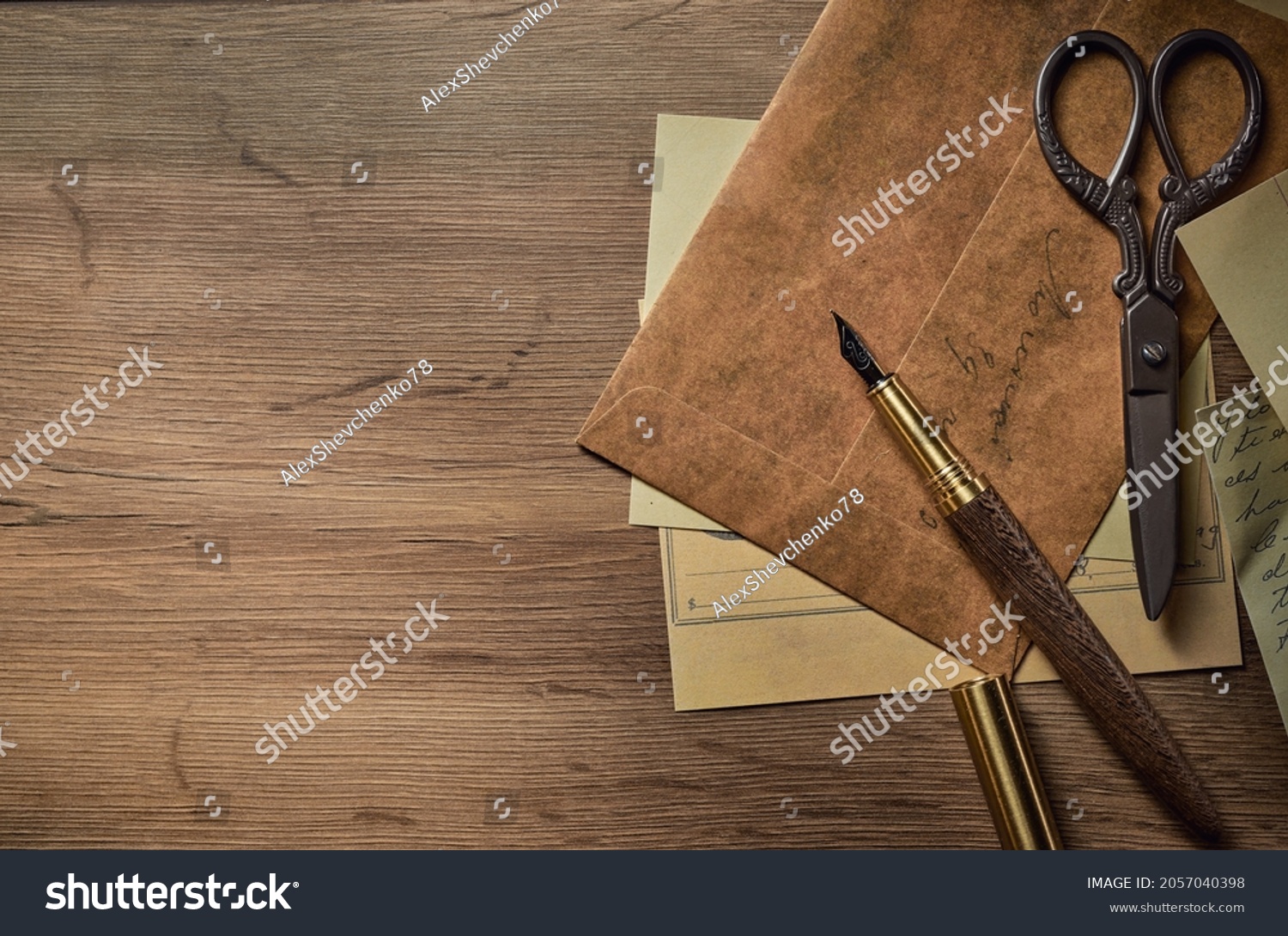 Vintage writing utensils on a wooden table, old watch, papers, letters, envelopes and scissors #2057040398