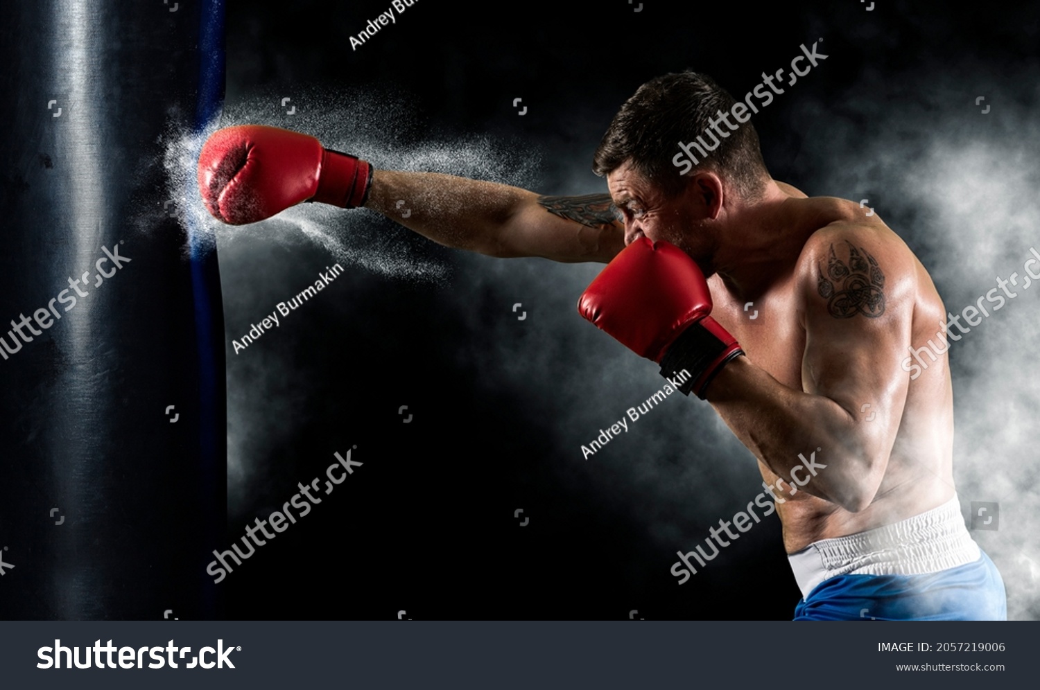 Boxer in red gloves at the moment of impact on punching bag. Sports banner. Horizontal copy space background #2057219006