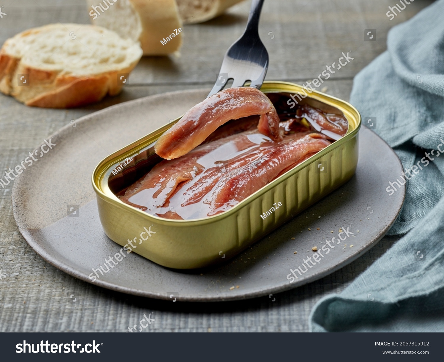 canned anchovy fillets and slices of baguette on wooden kitchen table #2057315912