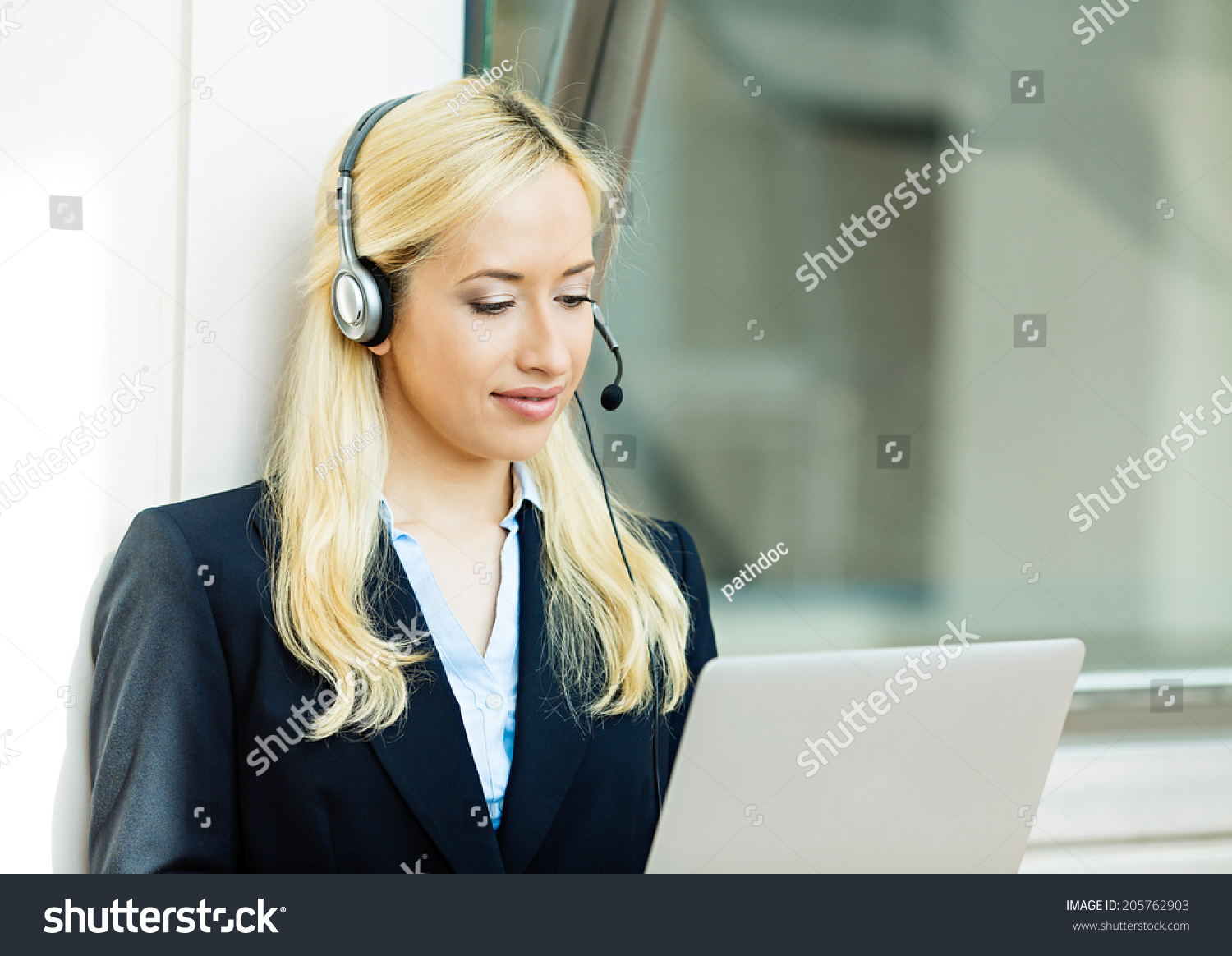 Closeup portrait young happy successful business woman, customer service representative, call centre worker, operator, support staff speaking with head set isolated background corporate office windows #205762903
