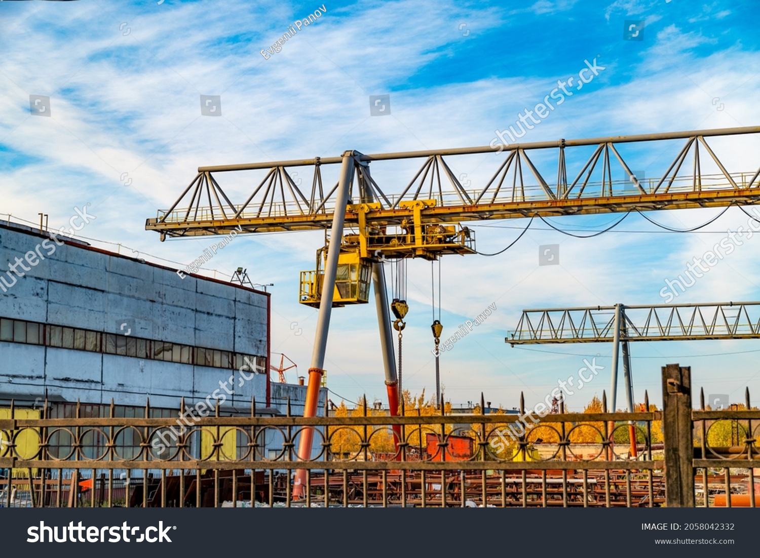 Cargo cranes at an industrial plant loads heavy goods and containers. The concept of logistics and business for the transportation and delivery of goods by sea, road and rail. #2058042332