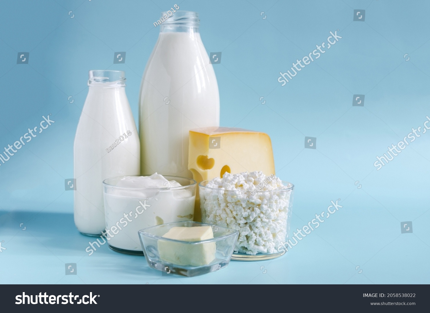 Dairy products in close - up in transparent dishes on a blue background . Milk, kefir, sour cream, cheese, butter and cottage cheese in a glass container on a light background #2058538022