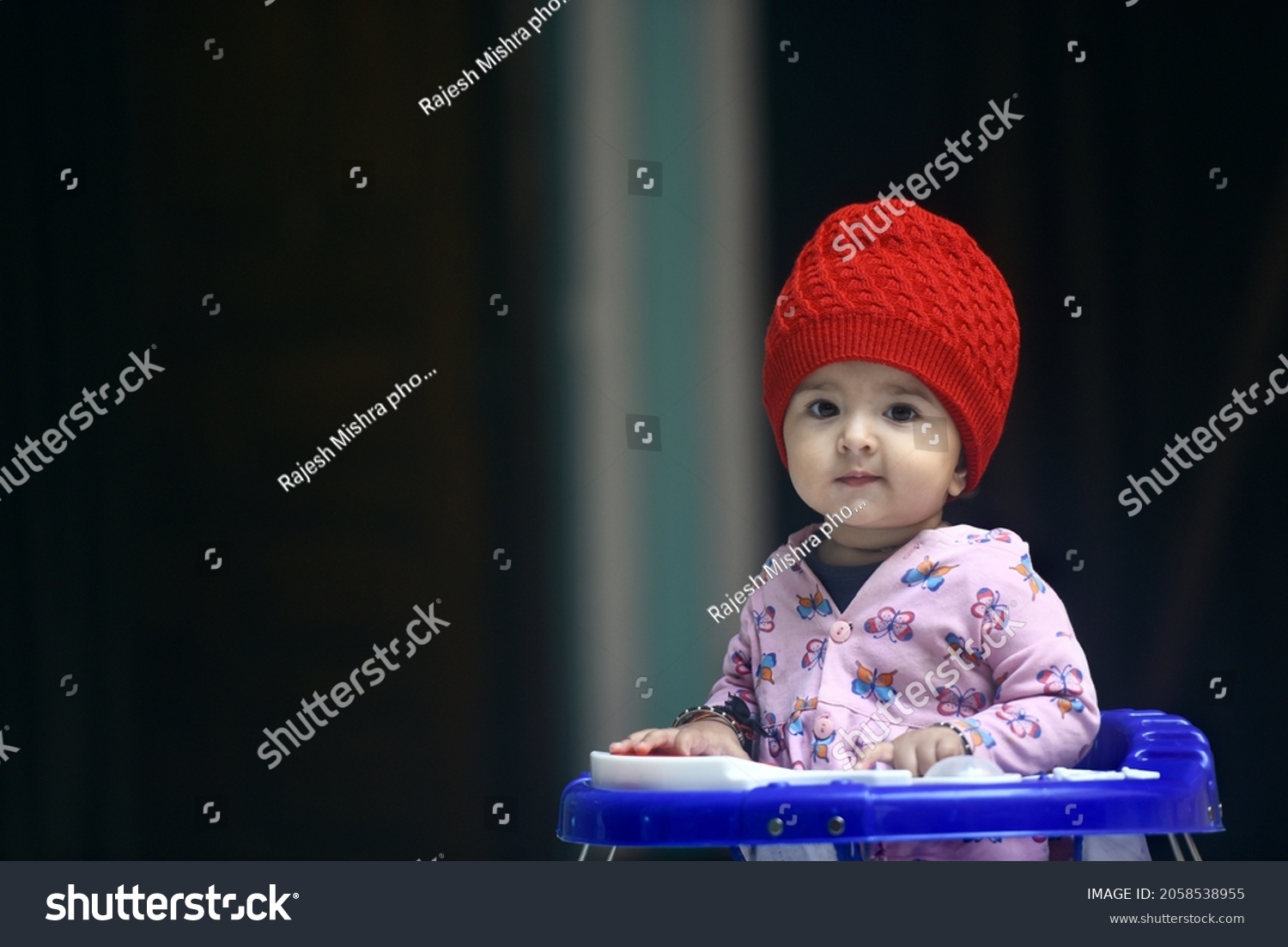 11 months old cute and innocent baby girl sitting in a walker and giving awesome expressions #2058538955