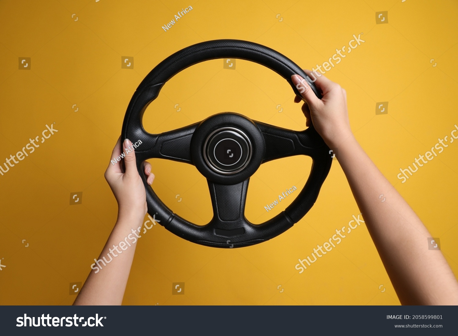 Woman holding steering wheel on yellow background, closeup #2058599801