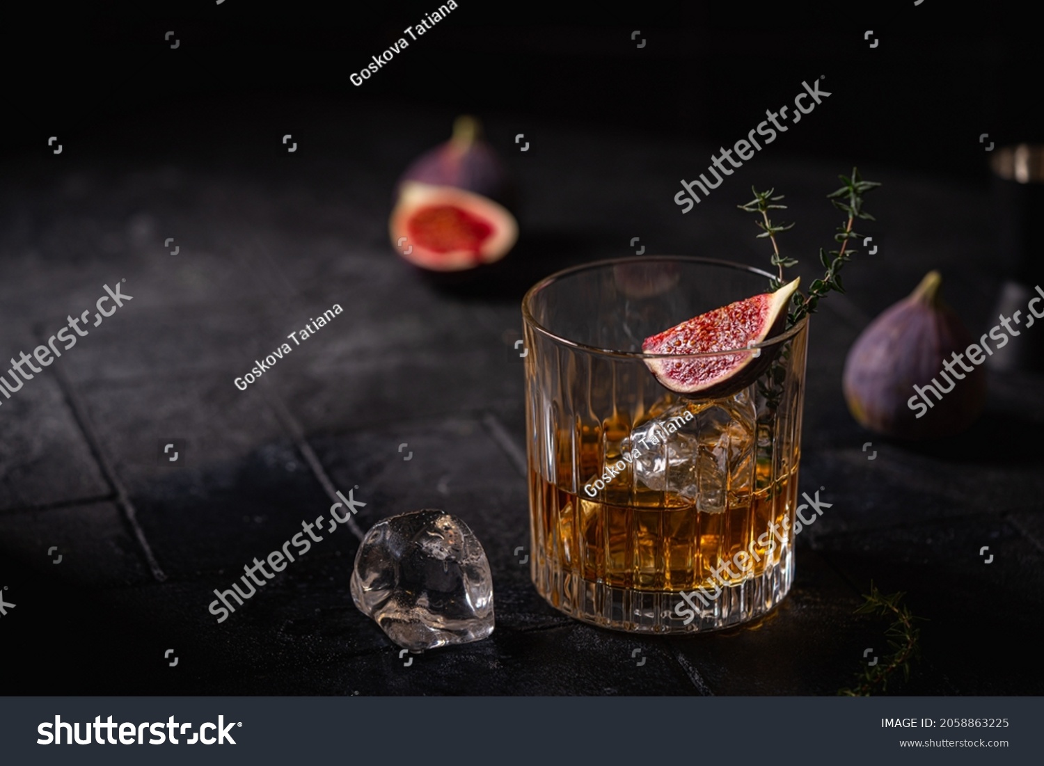 Single glass of whiskey with ice and figs on black background #2058863225