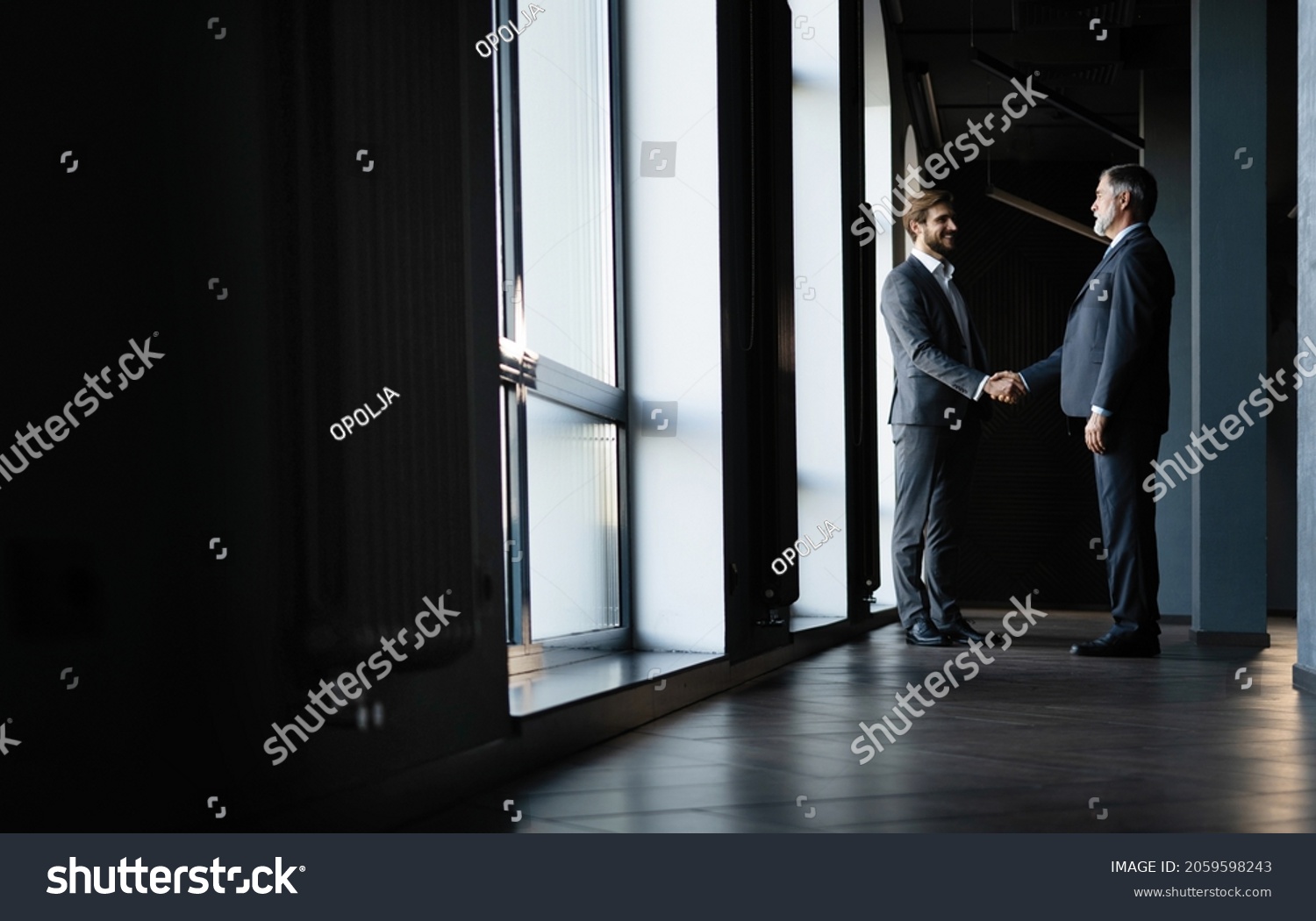 Full length view of businessmen shaking hands in office building #2059598243