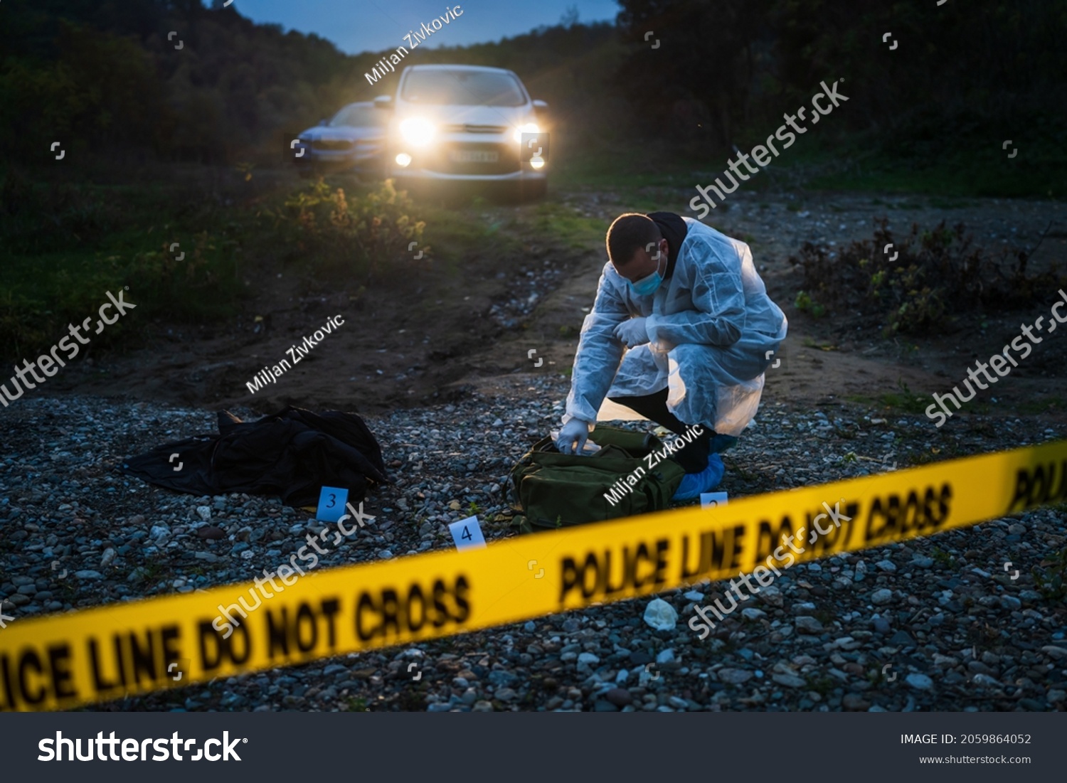 Forensic police investigator collecting evidence at the crime scene in nature at night #2059864052