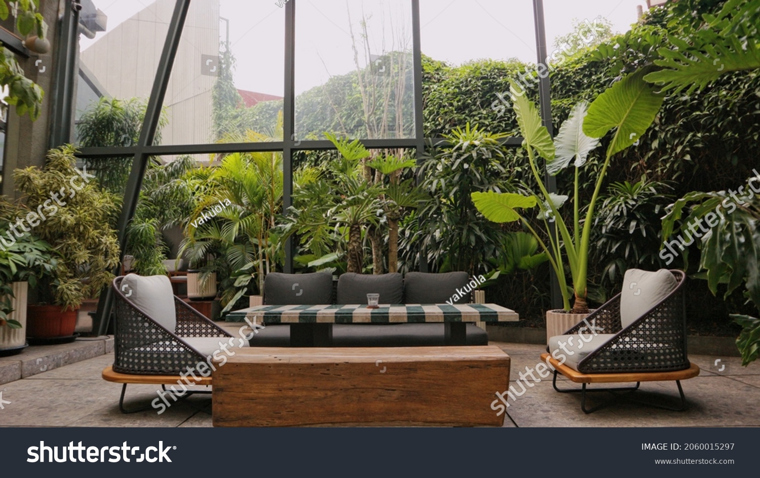 Modern living room with gray sofa and green tropical ferns outdoors #2060015297