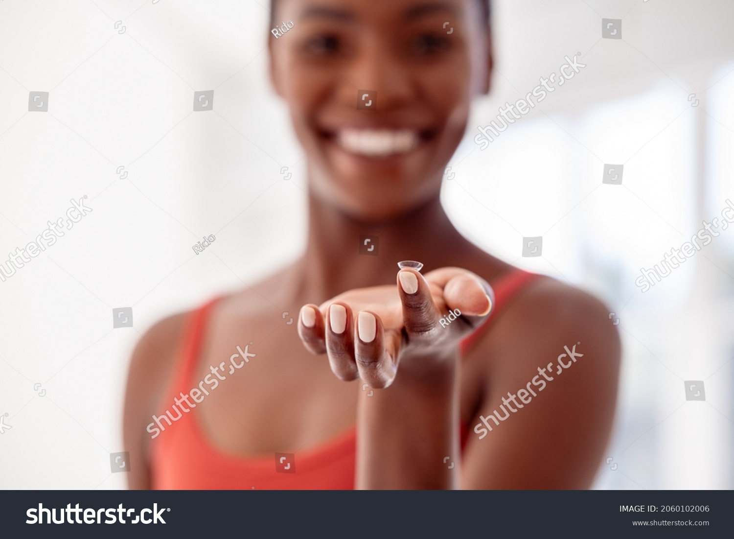 Close up of contact lens on finger of young african woman. Mature black woman holding contact lens in front of her face. Happy smiling woman showing contact lens. #2060102006
