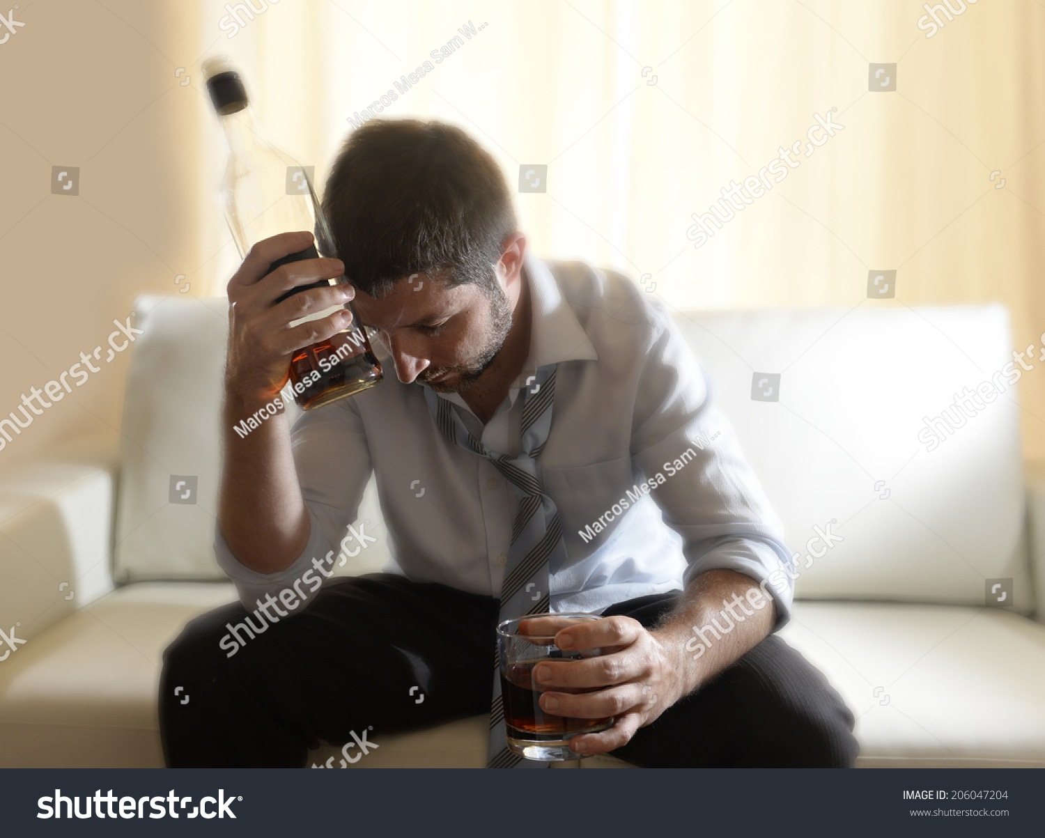  drunk business man at home lying asleep on couch sleeping wasted holding whiskey glass indoors in alcoholism problem , alcohol abuse and addiction concept looking messy and sick  #206047204