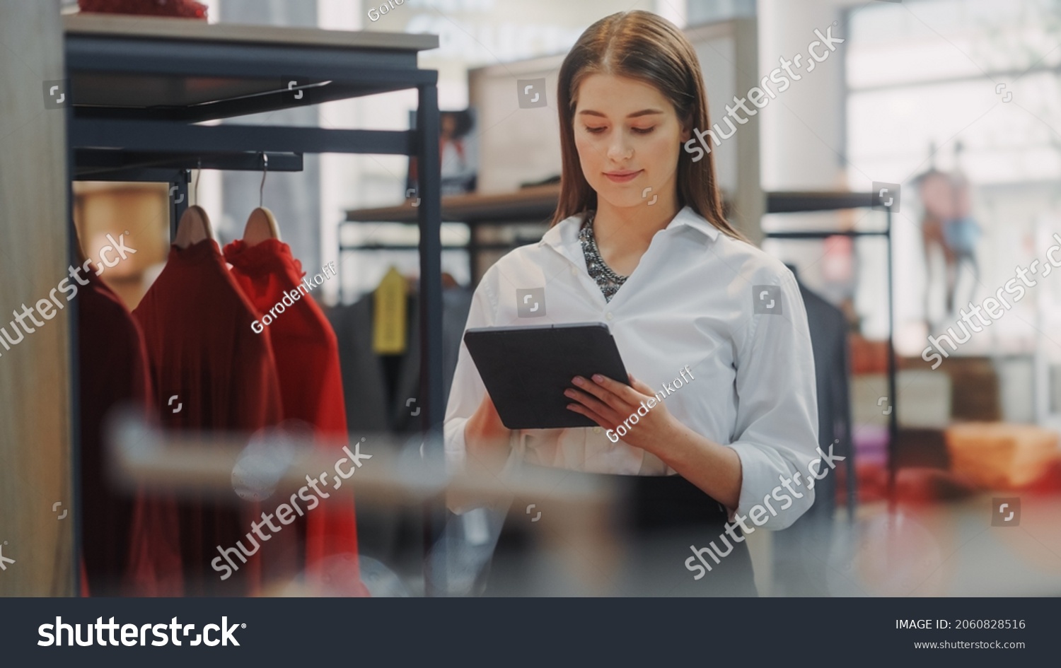 Clothing Store: Female Visual Merchandising Specialist Uses Tablet Computer To Create Stylish Collection. Fashion Shop Sales Retail Manager Checks Stock. Small Business Owner Orders Merchandise #2060828516
