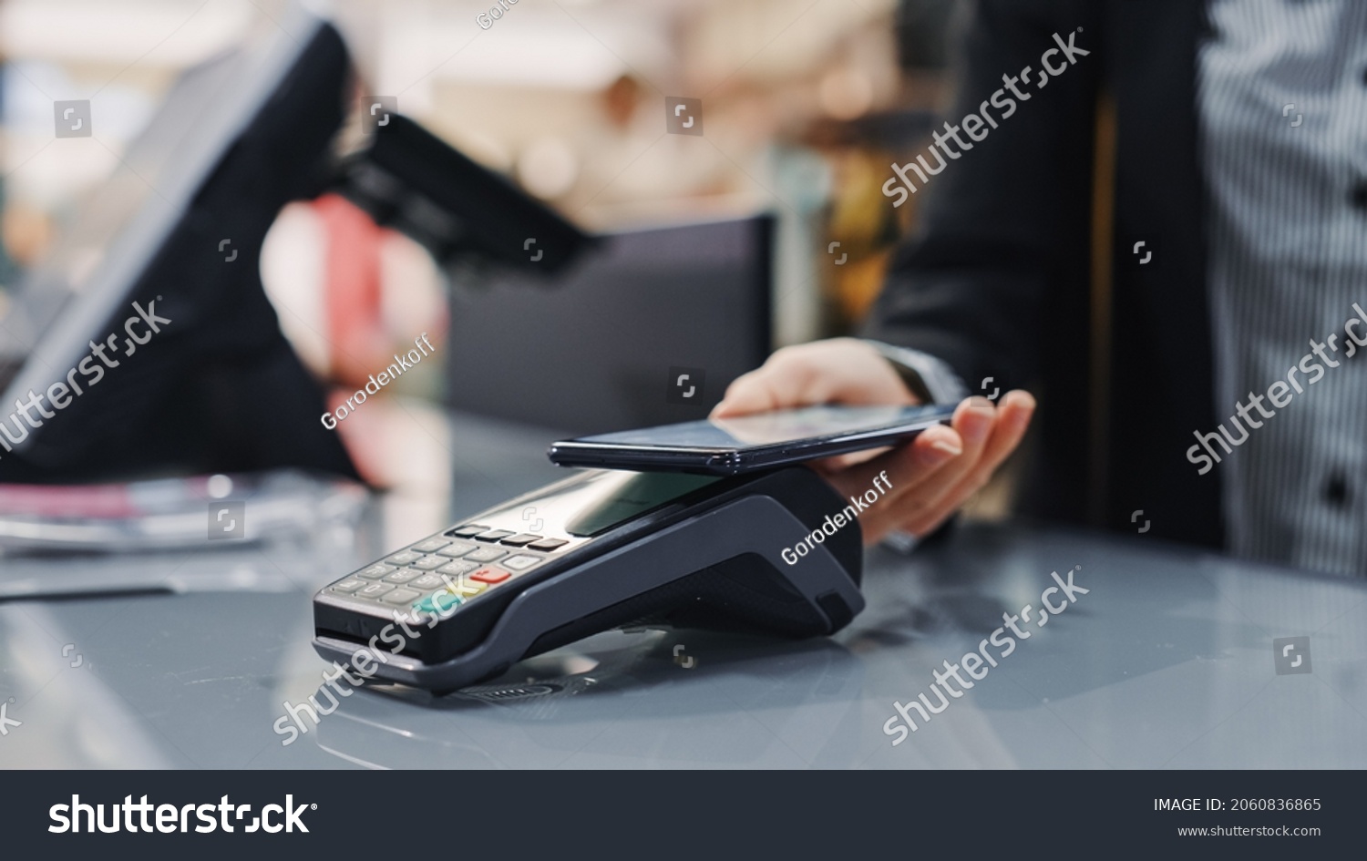 Clothing Store: Woman At Counter Buys Clothes Paying with Smartphone Through, Contactless NFC Terminal. Department Store, Shopping Center, Mall Purchase. Close-up Focus on Mobile Phone #2060836865