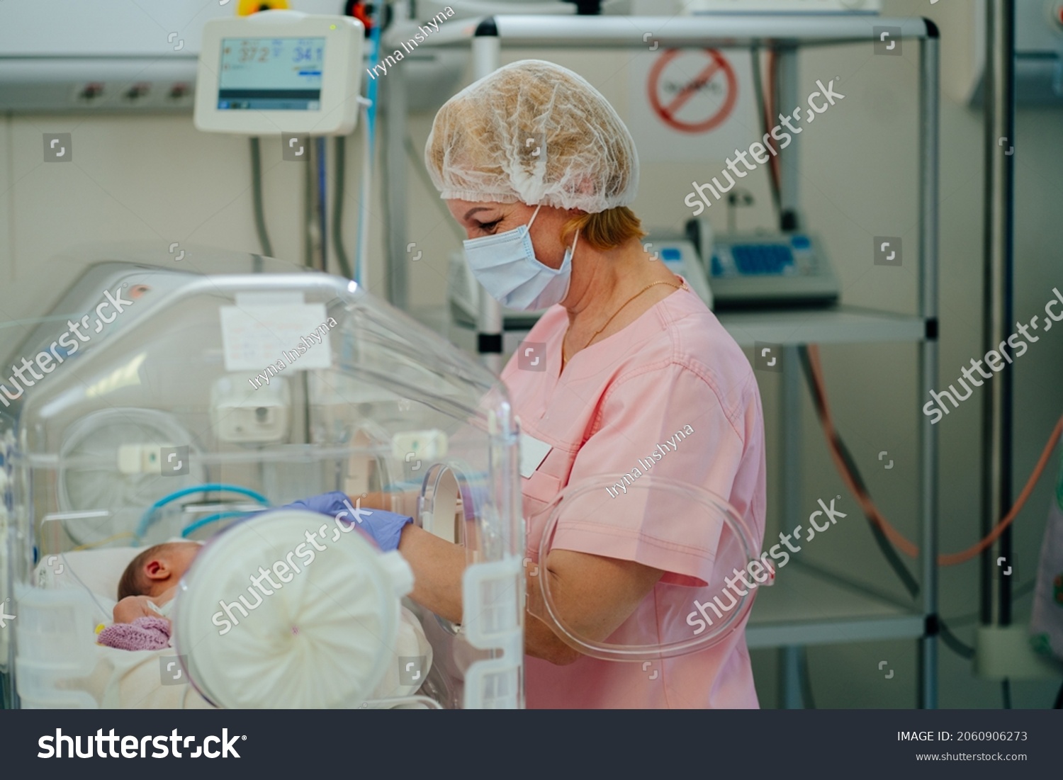 At the intensive care unit. Nurse standing near hospital bed with a baby preparing it for treatment. Newborn is placed in the incubator. Neonatal intensive care unit #2060906273