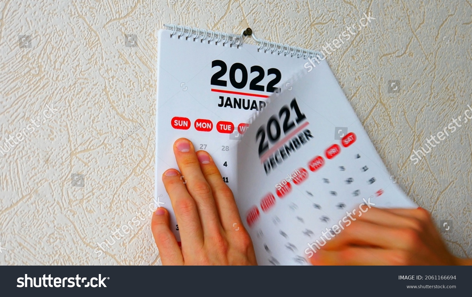 Close-up of a man's hands tearing off the December page of a 2021 calendar on the wall followed by the January page of a new 2022 calendar #2061166694