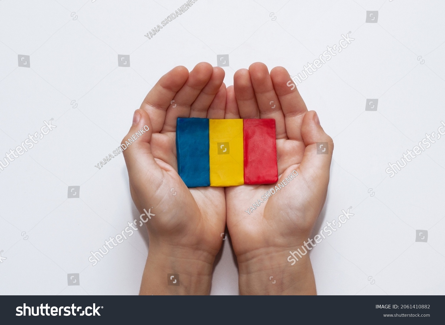 flag of Romania made of plasticine in the hands of a child on a white background #2061410882