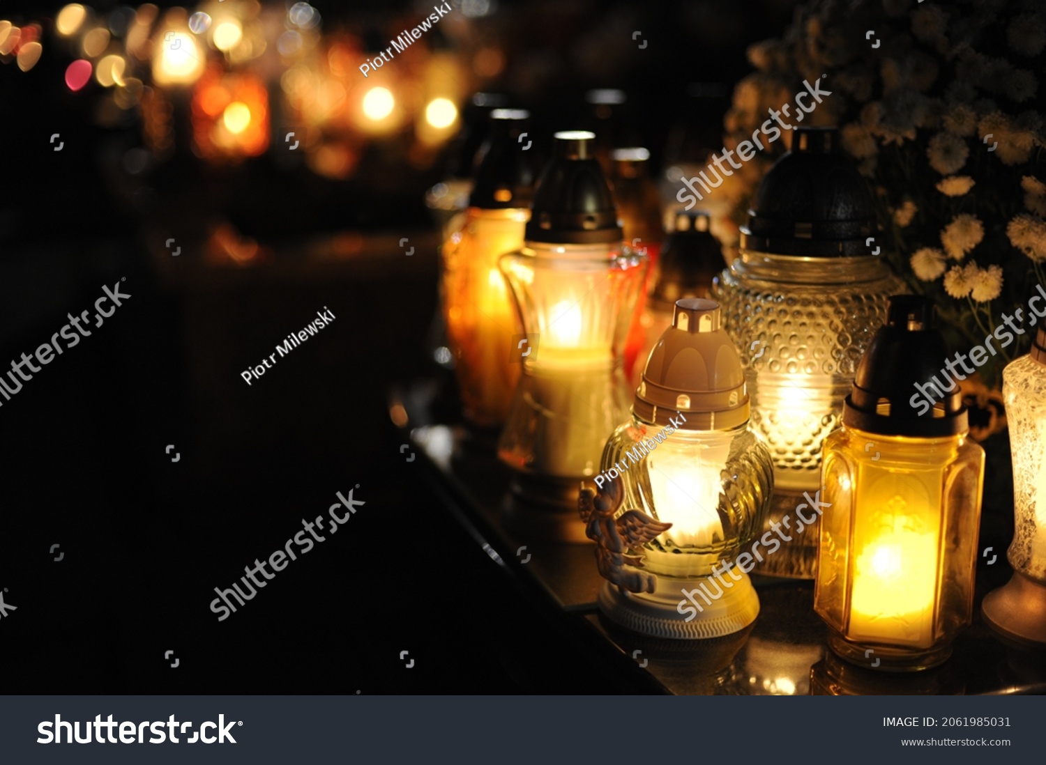 Candle lights on graves and tombstones in cemetery at night in Poland on All Saints’ Day or All Souls’ Day or Halloween or Zaduszki or Day of the Dead #2061985031