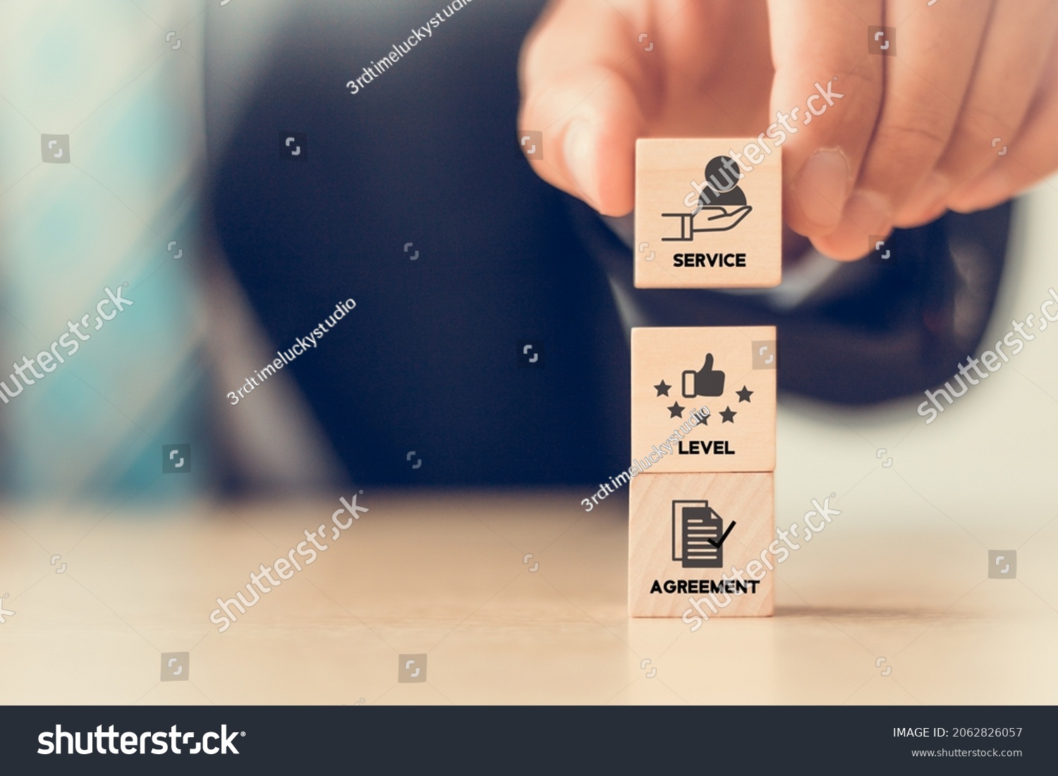 SLA - Service Level Agreement acronym, business concept. Service performance tracking to reduce the uncertainty the customer in process. Hand holds  wooden cubes with Service Level Agreement symbols. #2062826057