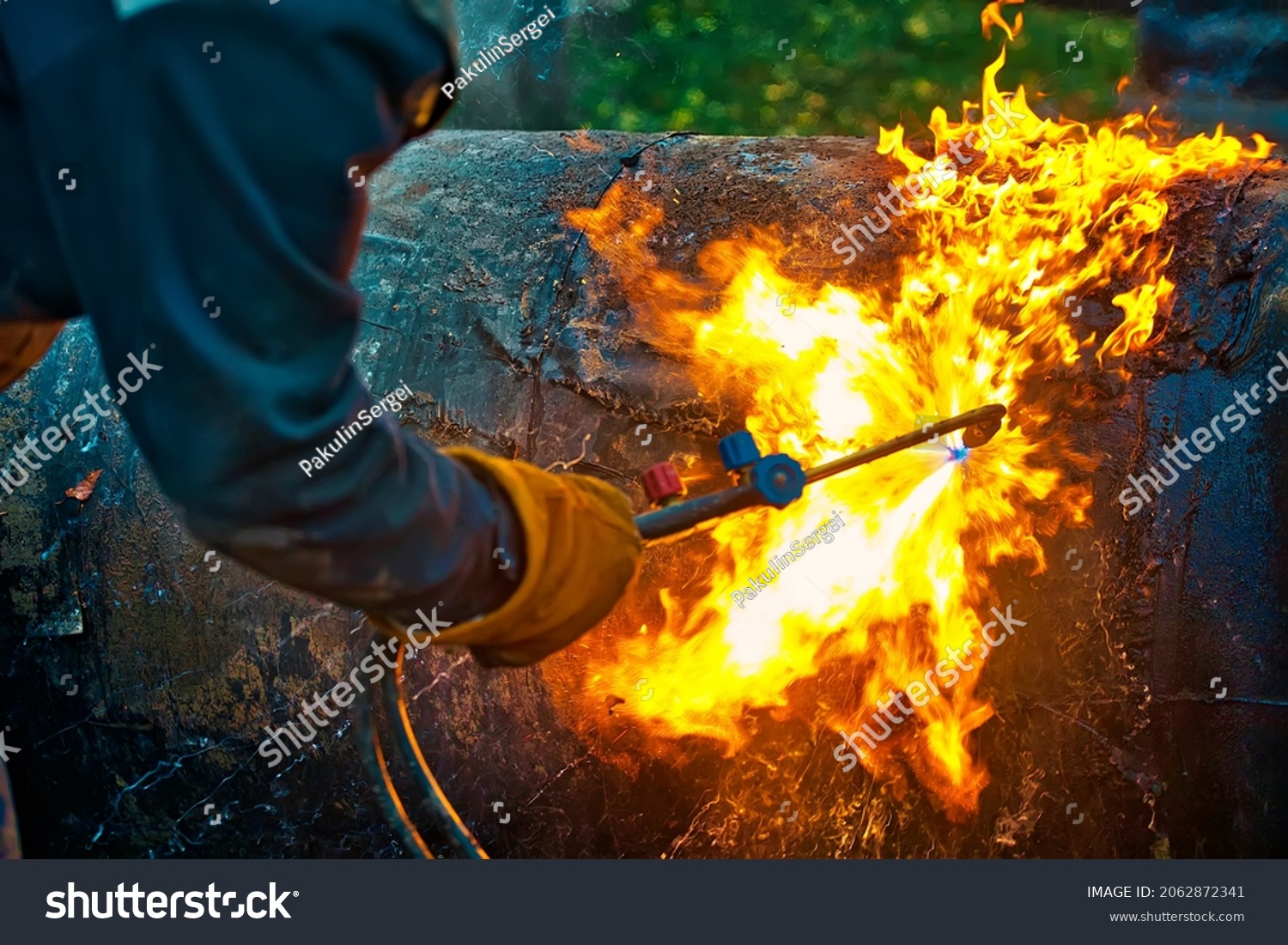 The texture of hot metal from acetylene welding. Welder's hands in protective gloves during operation. Cutting a metal pipe outside during the day. #2062872341