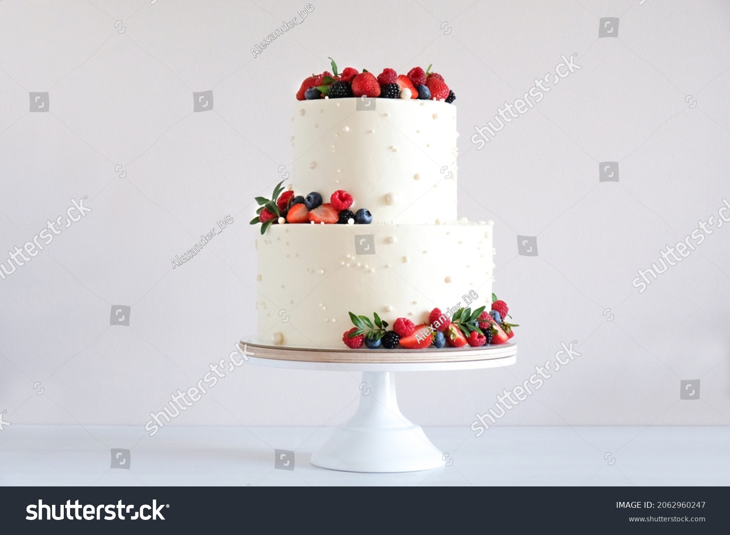 White wedding cake, with slices strawberries, raspberries, blackberry on a white background. #2062960247