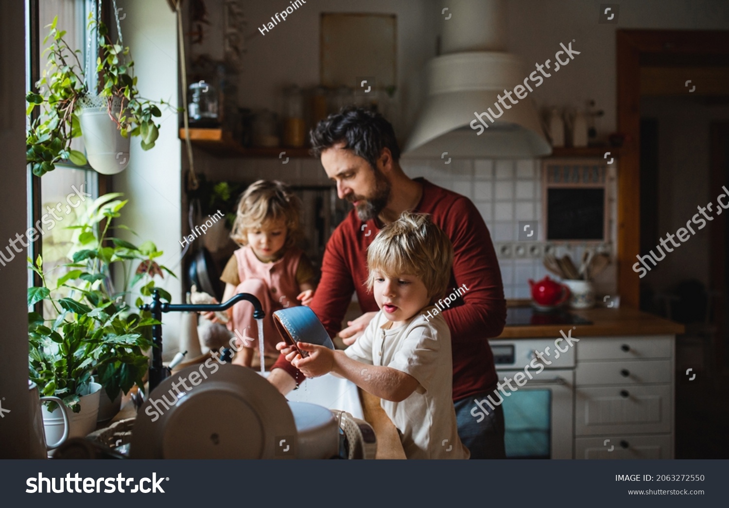 Mature father with two small children washing dishes indoors at home, daily chores concept. #2063272550