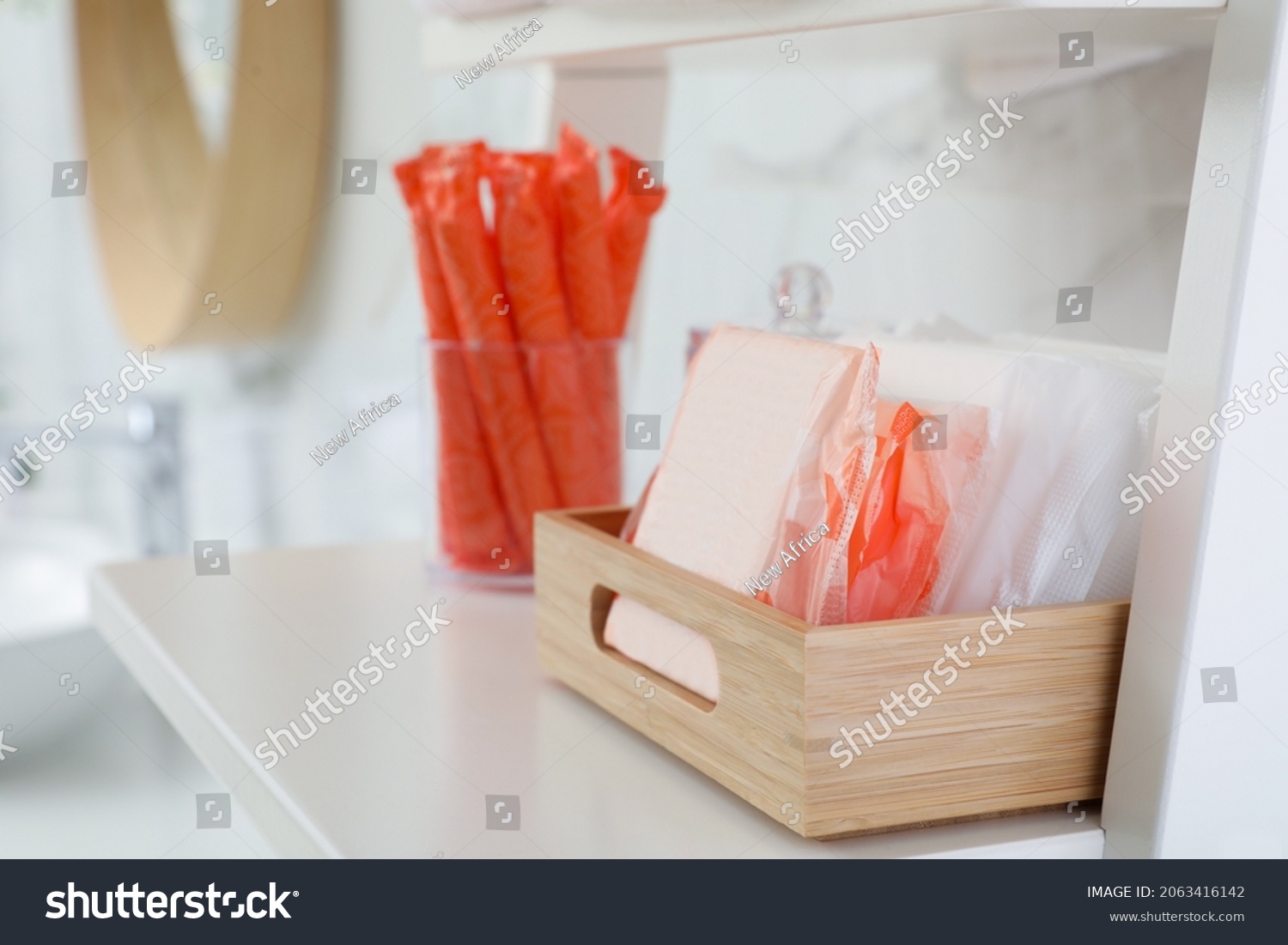 Organizer with tampons and menstrual pads on shelving unit in bathroom. Feminine hygiene products #2063416142
