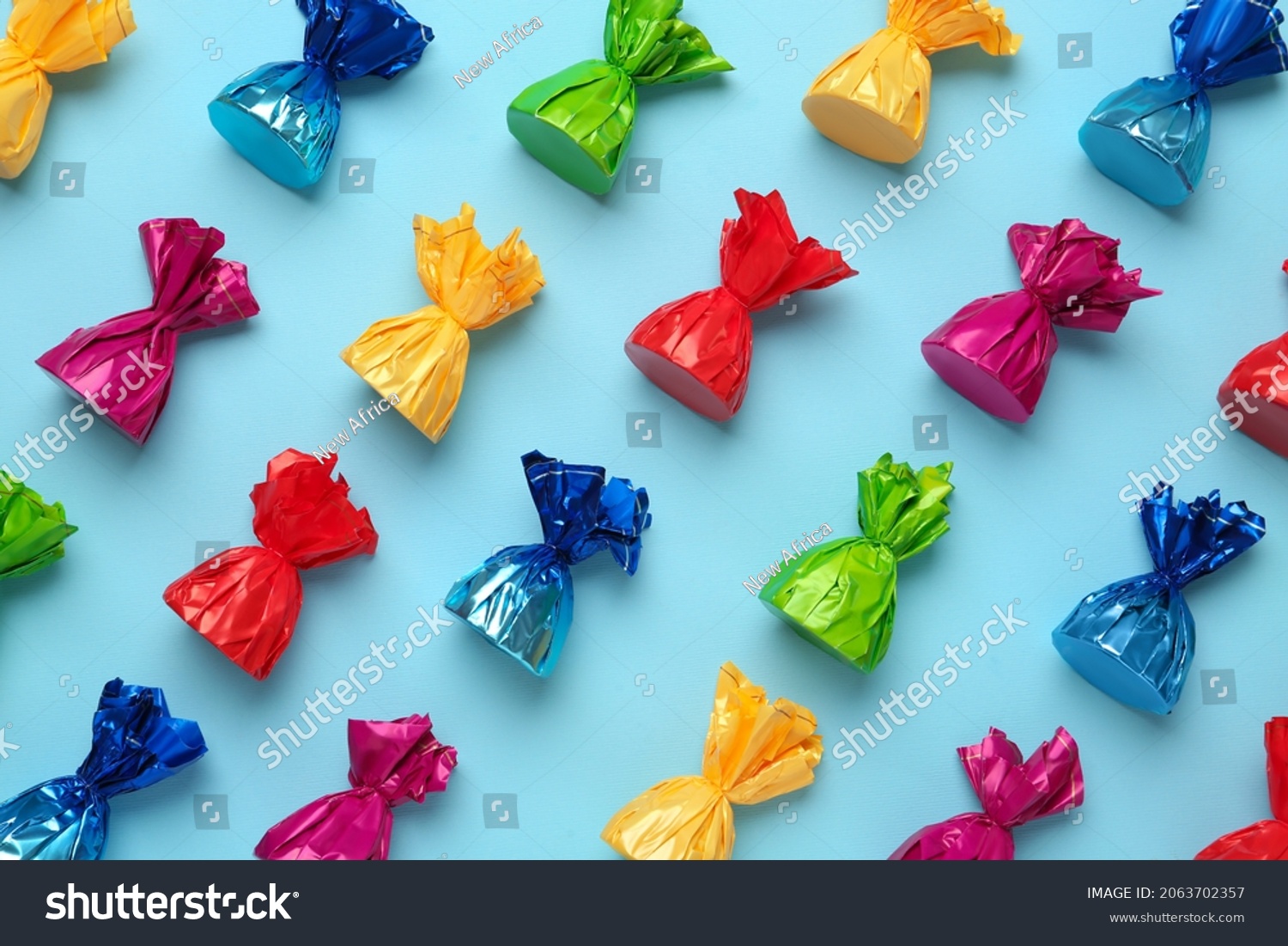 Candies in colorful wrappers on light blue background, flat lay #2063702357