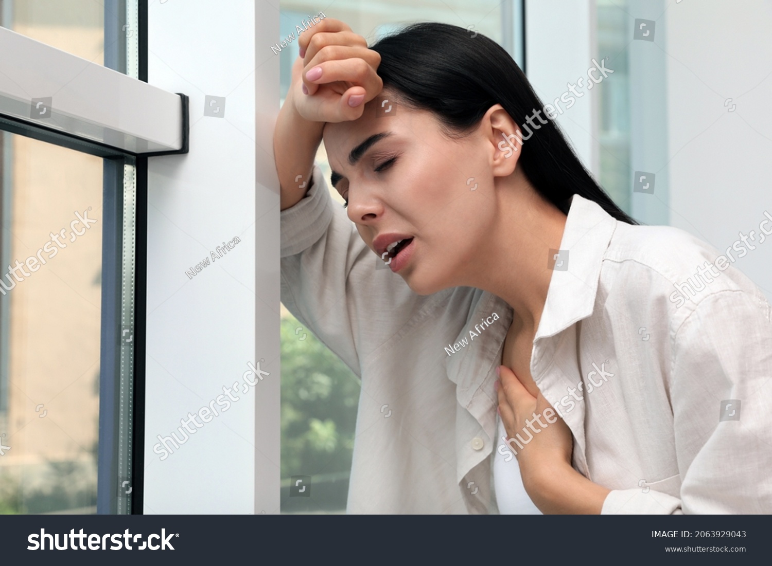 Young woman suffering from breathing problem near window indoors #2063929043