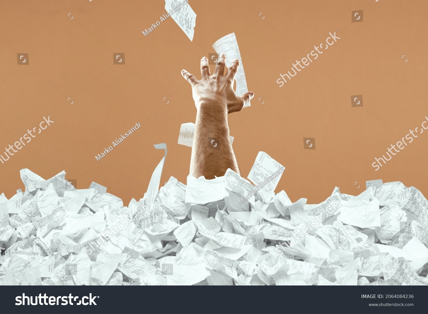 A man's hand sticks out of a mountain of checks and bills. A man is drowning in debt, credit, mortgage, loan, mortgage #2064084236
