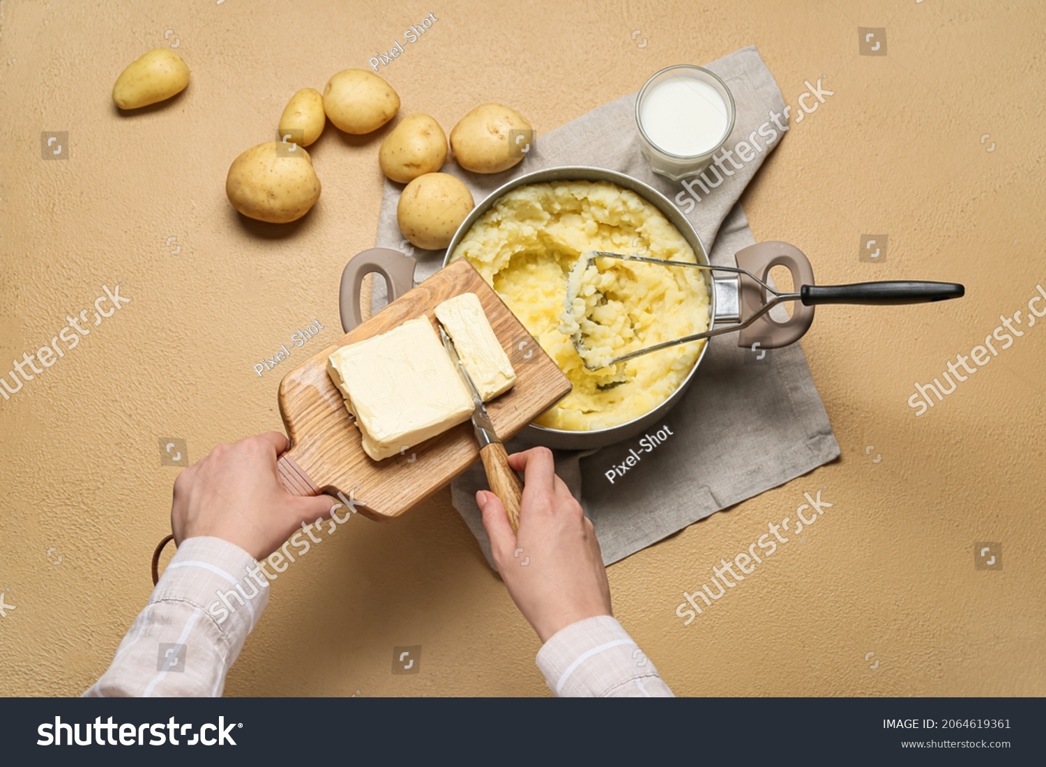 Woman adding butter into pot with tasty mashed potatoes on color background #2064619361